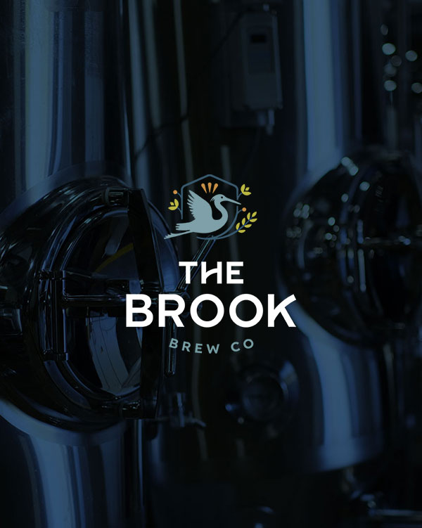 The Brook Brew Co. logo set on a background image of brewery tanks.